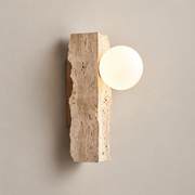 Aureum Travertine Globe Wall Sconce on a warm greige background; Beige rough cruciform stone, white globe
