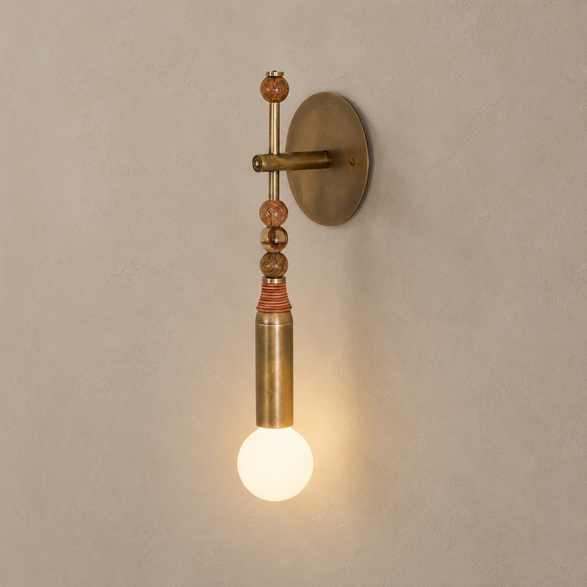 Toam brass wall sconce with brown marble beads on a warm taupe wall