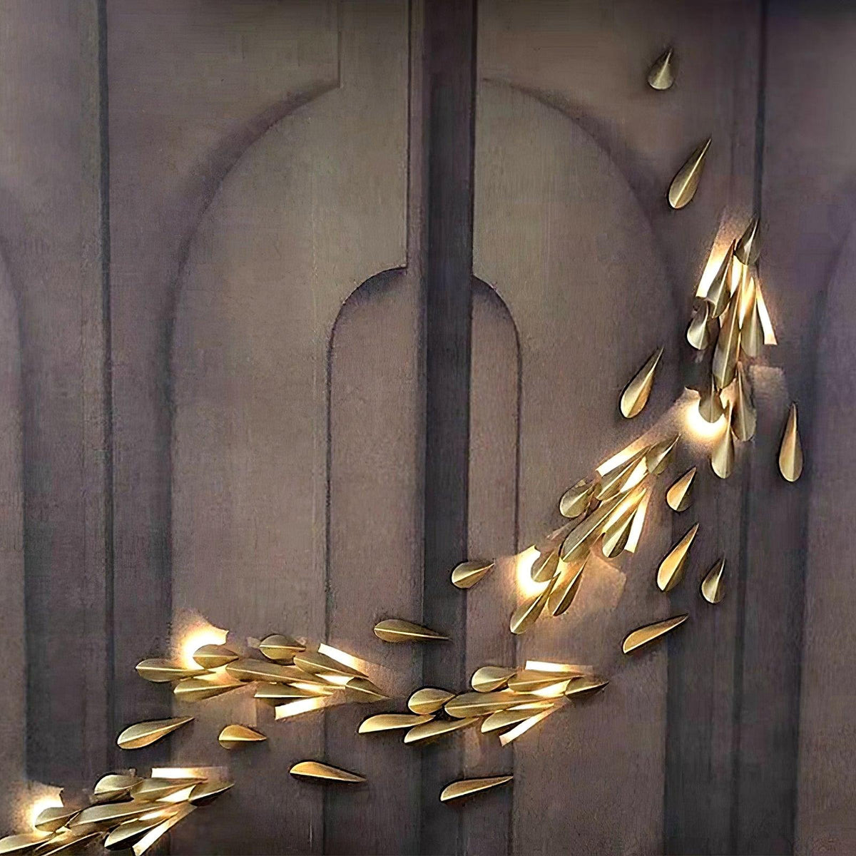 1273 large brass leaf wall light glowing on a dark architectural wall