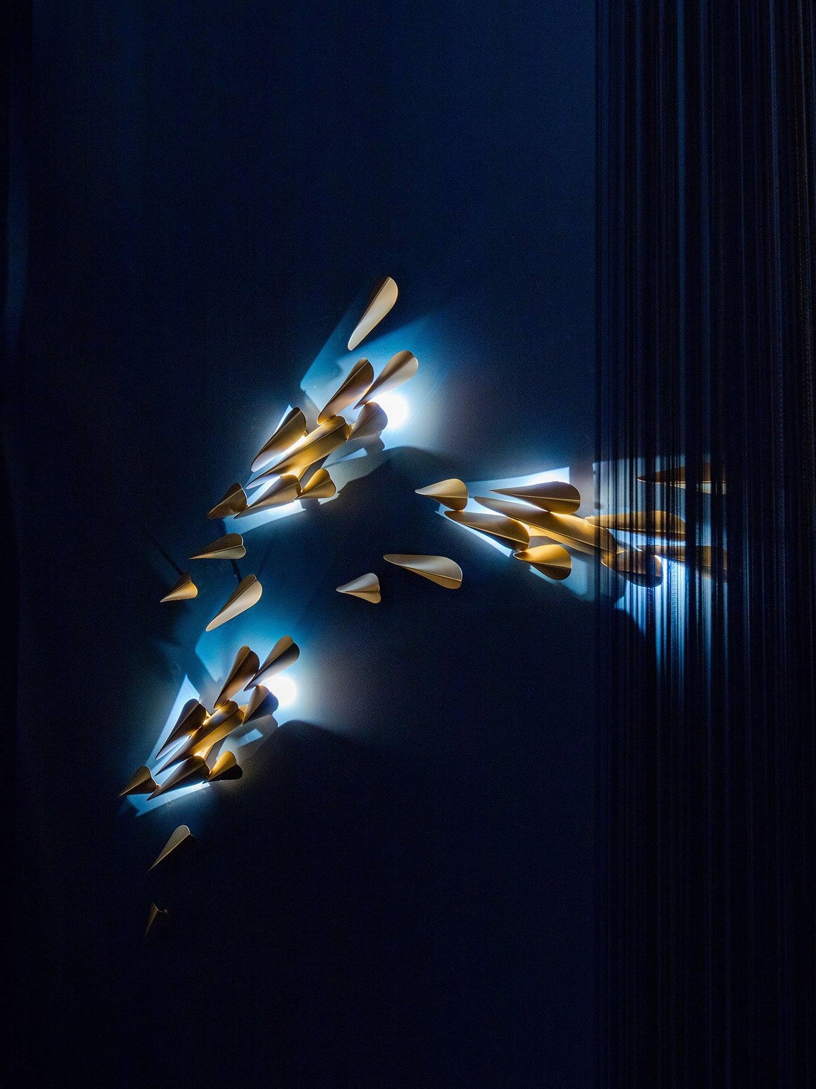 1273 large brass leaf wall light illuminated against a dark blue wall