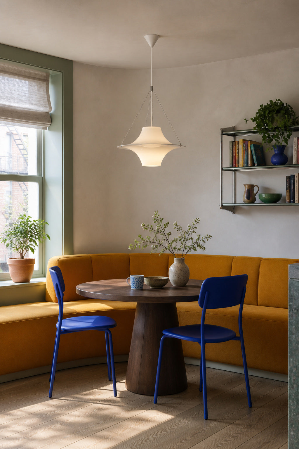 White acrylic saucer pendant above a colorful ochre banquette breakfast nook