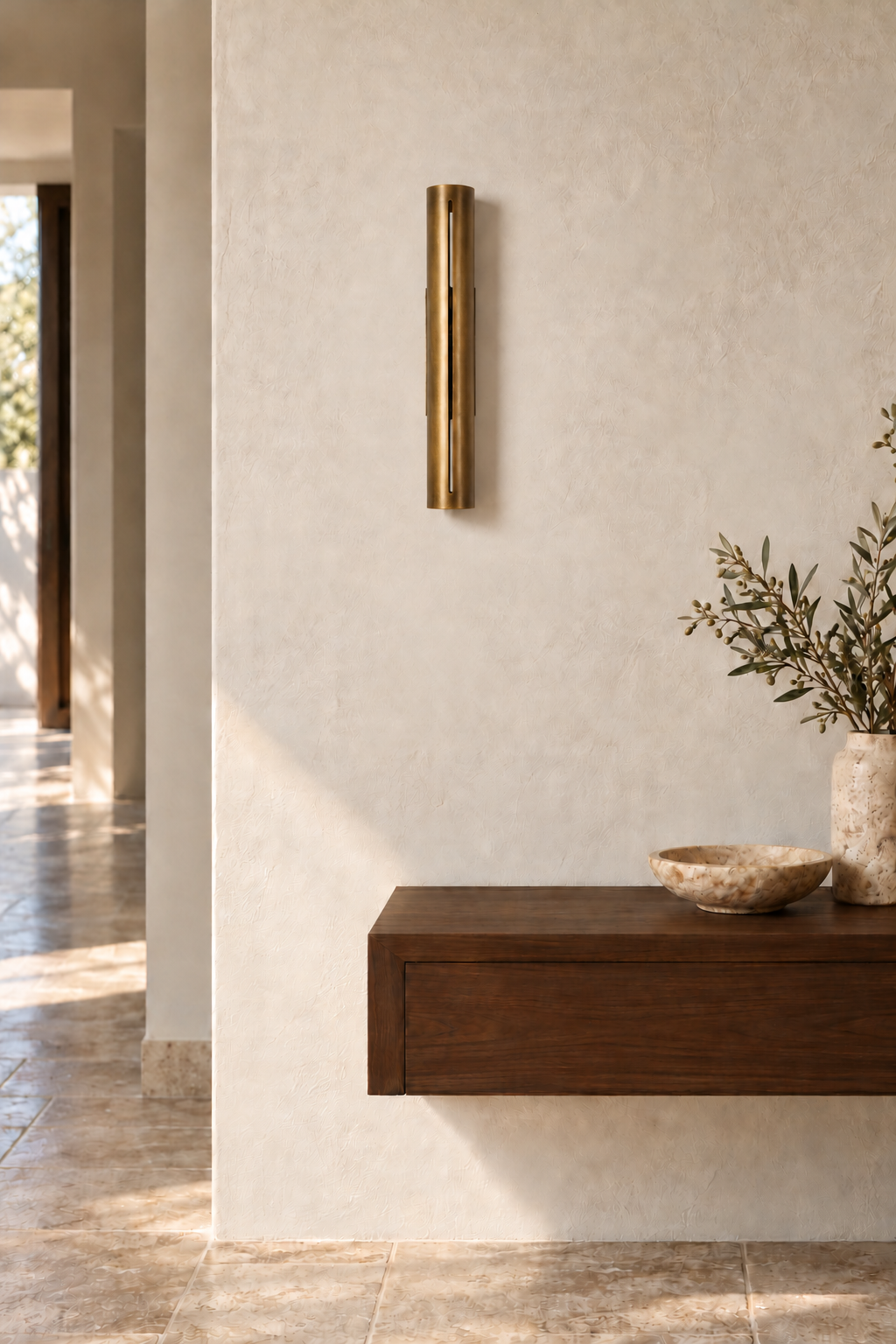 Long Antique Brass cylinder wall sconce styled in an entryway, with the light off.