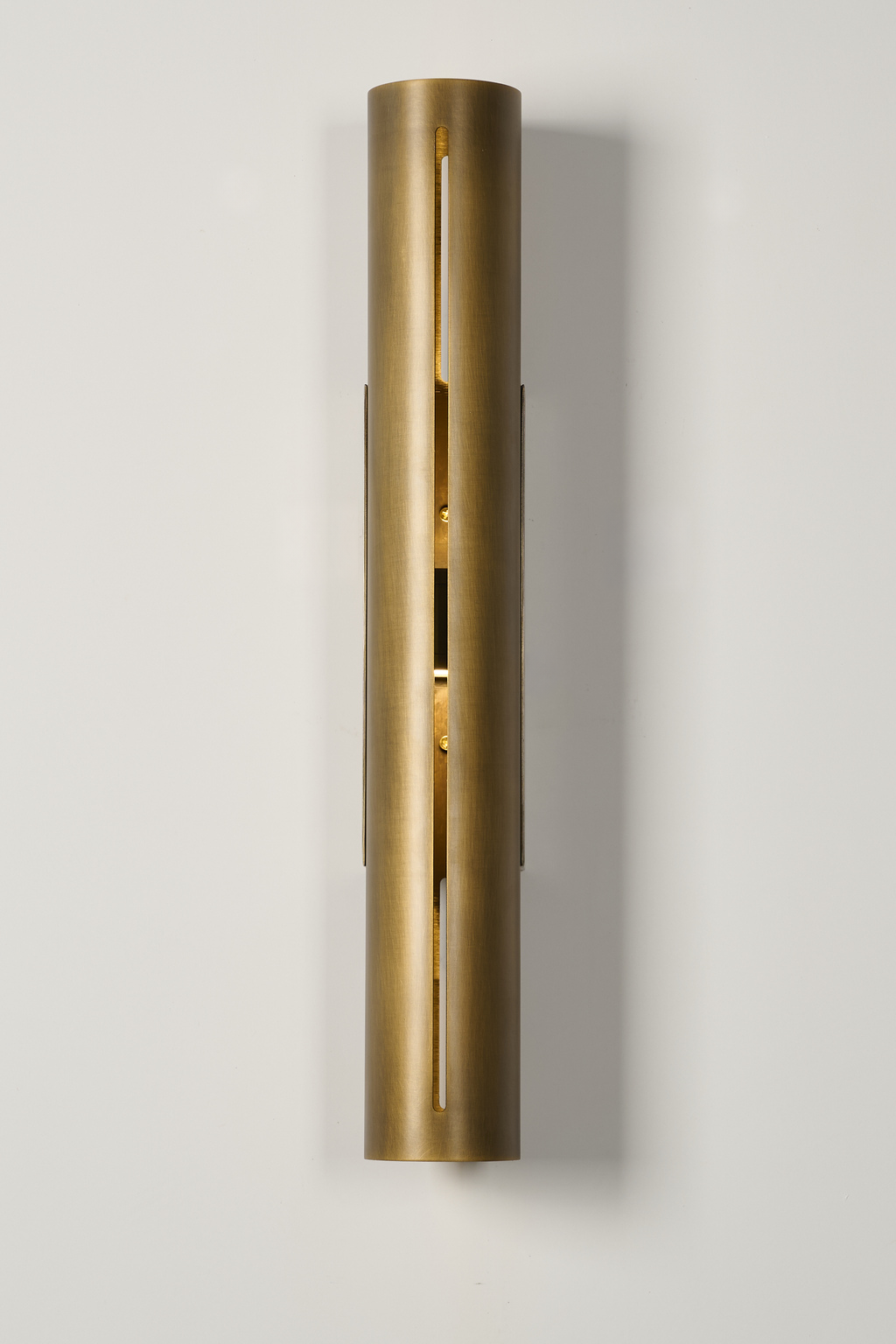 Long antique brass cylinder wall sconce, illuminated front view