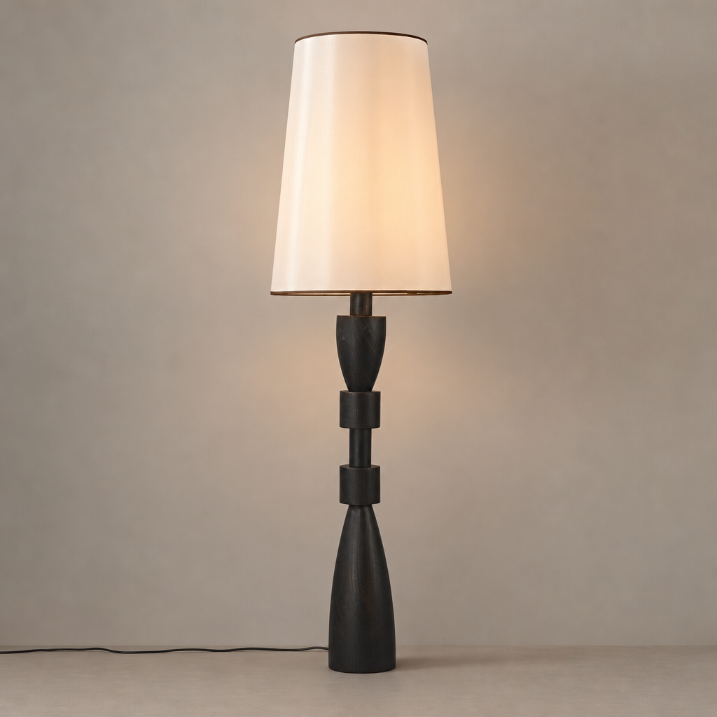 Sculptural black camphor wood floor lamp with a white fabric shade on a warm neutral background