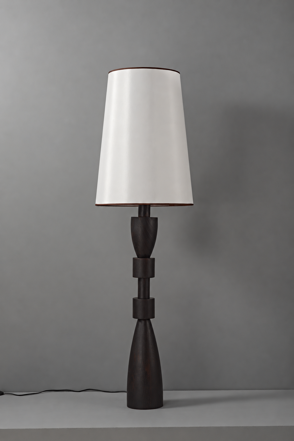 Camphor wood floor lamp switched off, with tapered fabric shade, sculptural stem and complete base
