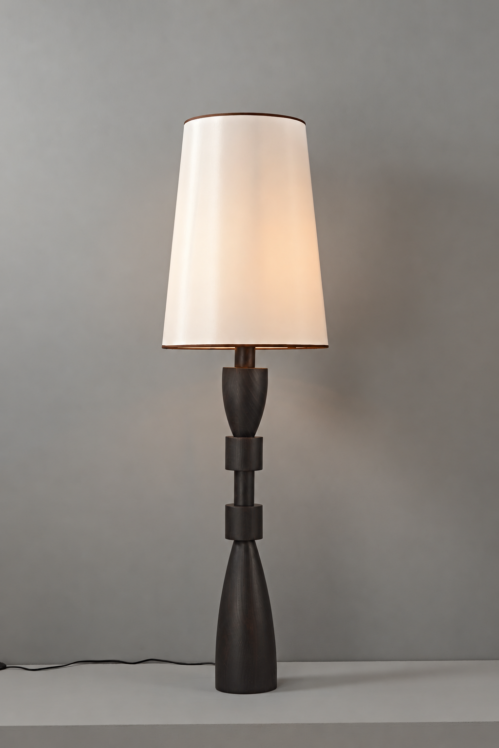 Camphor wood floor lamp illuminated, showing warm light through the white fabric shade