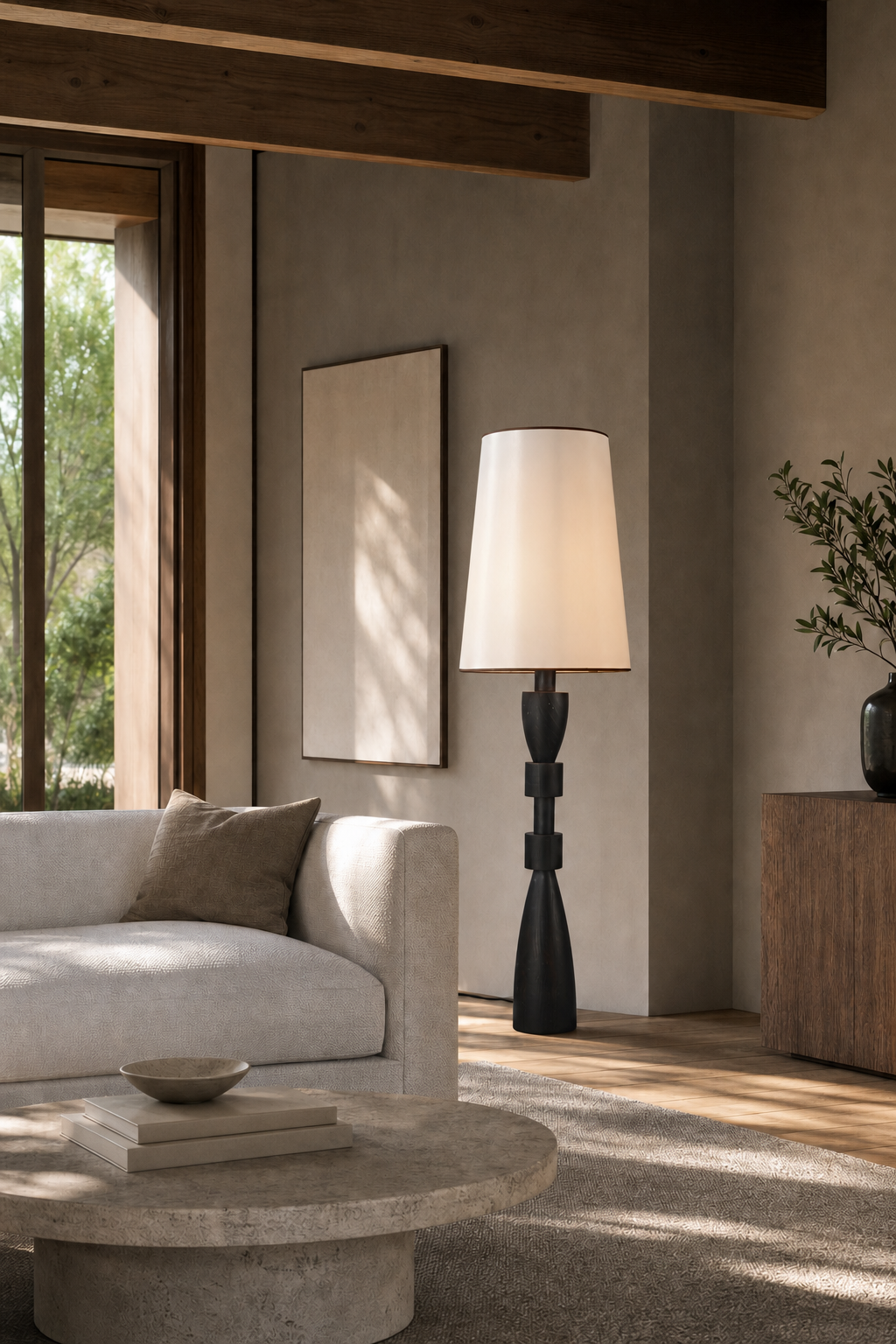Camphor wood floor lamp beside a curved sofa and round stone coffee table
