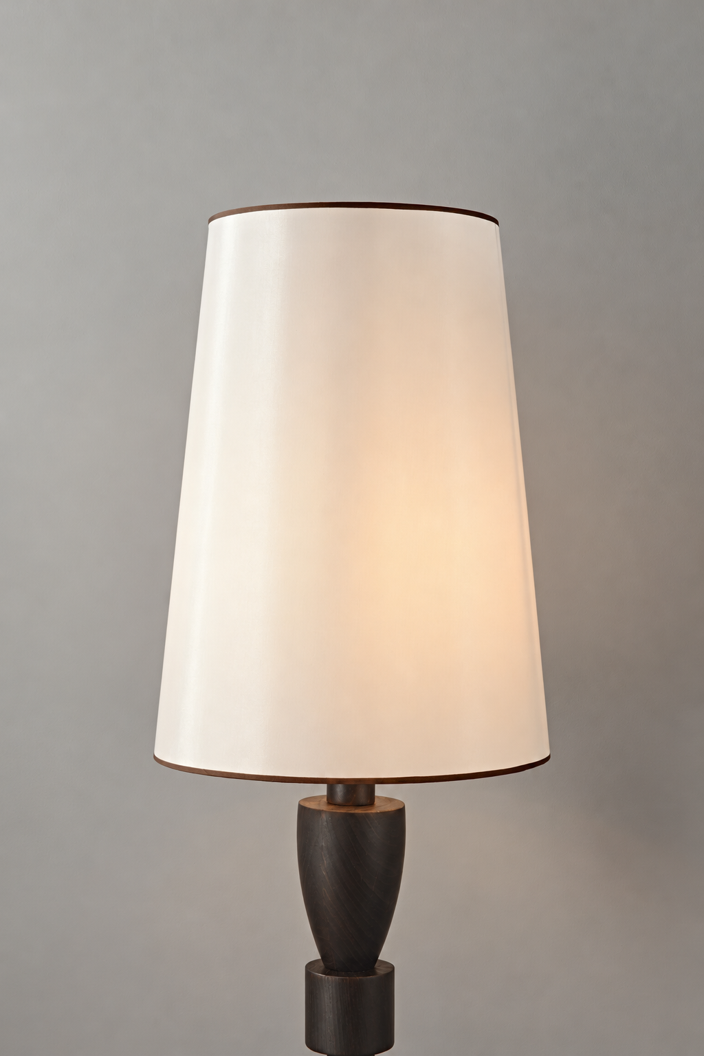 White fabric lampshade with dark edge trim above the camphor wood body