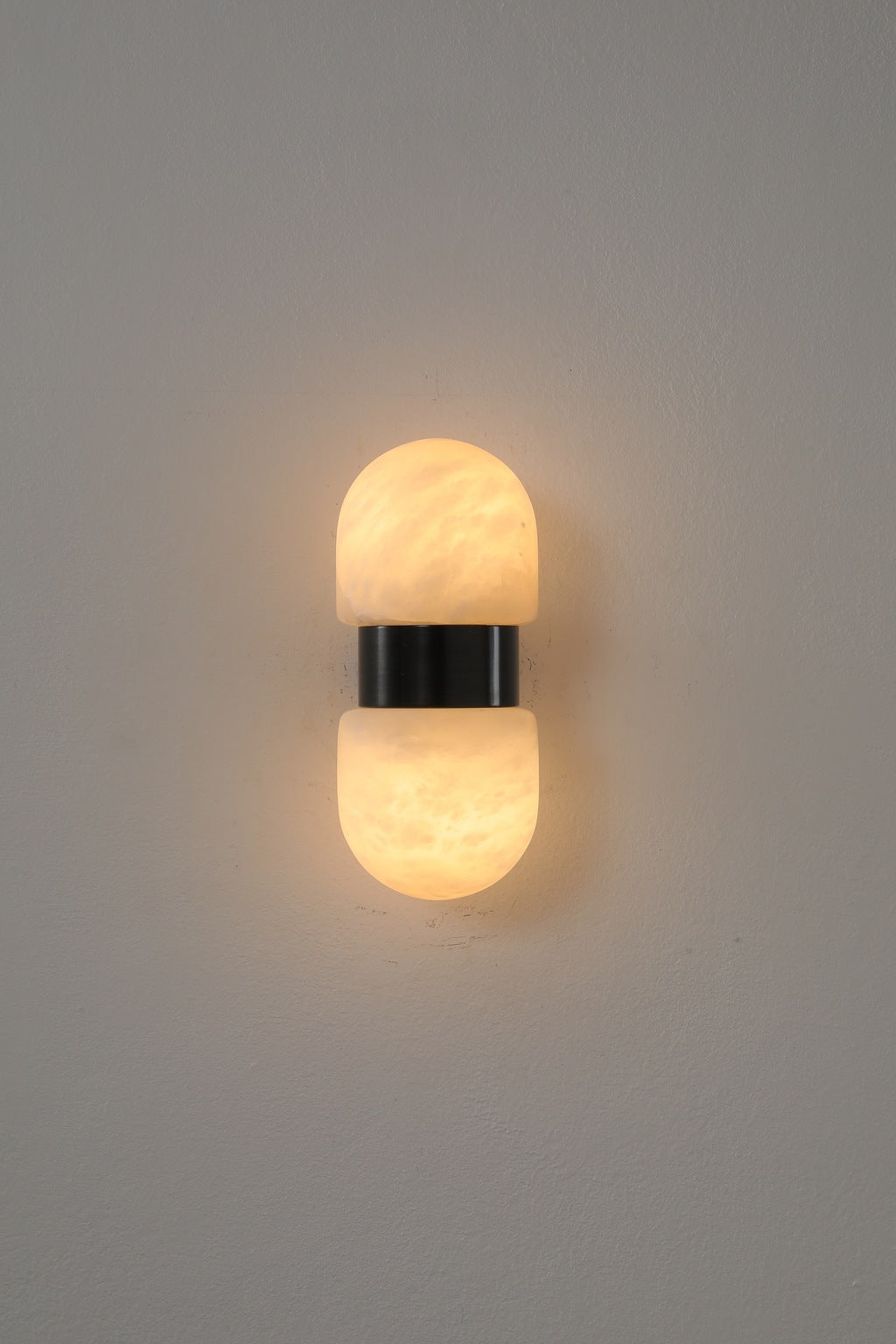 Alabaster Double Capsule Wall Sconce — Black with gold accents front view illuminated