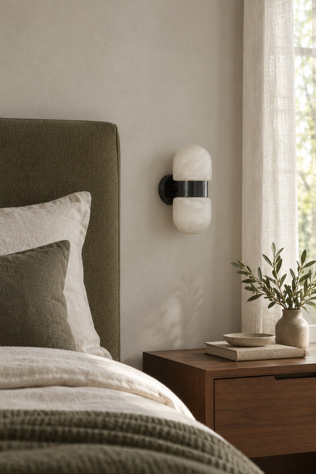 Alabaster Double Capsule Wall Sconce — Unlit black sconce beside a bed