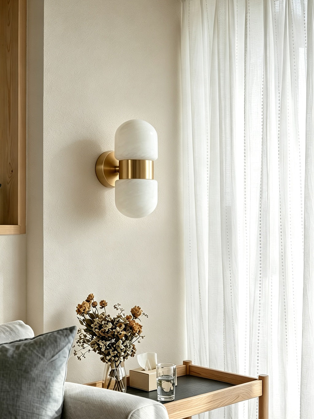 Alabaster Double Capsule Wall Sconce — Natural copper sconce beside curtains and a sofa