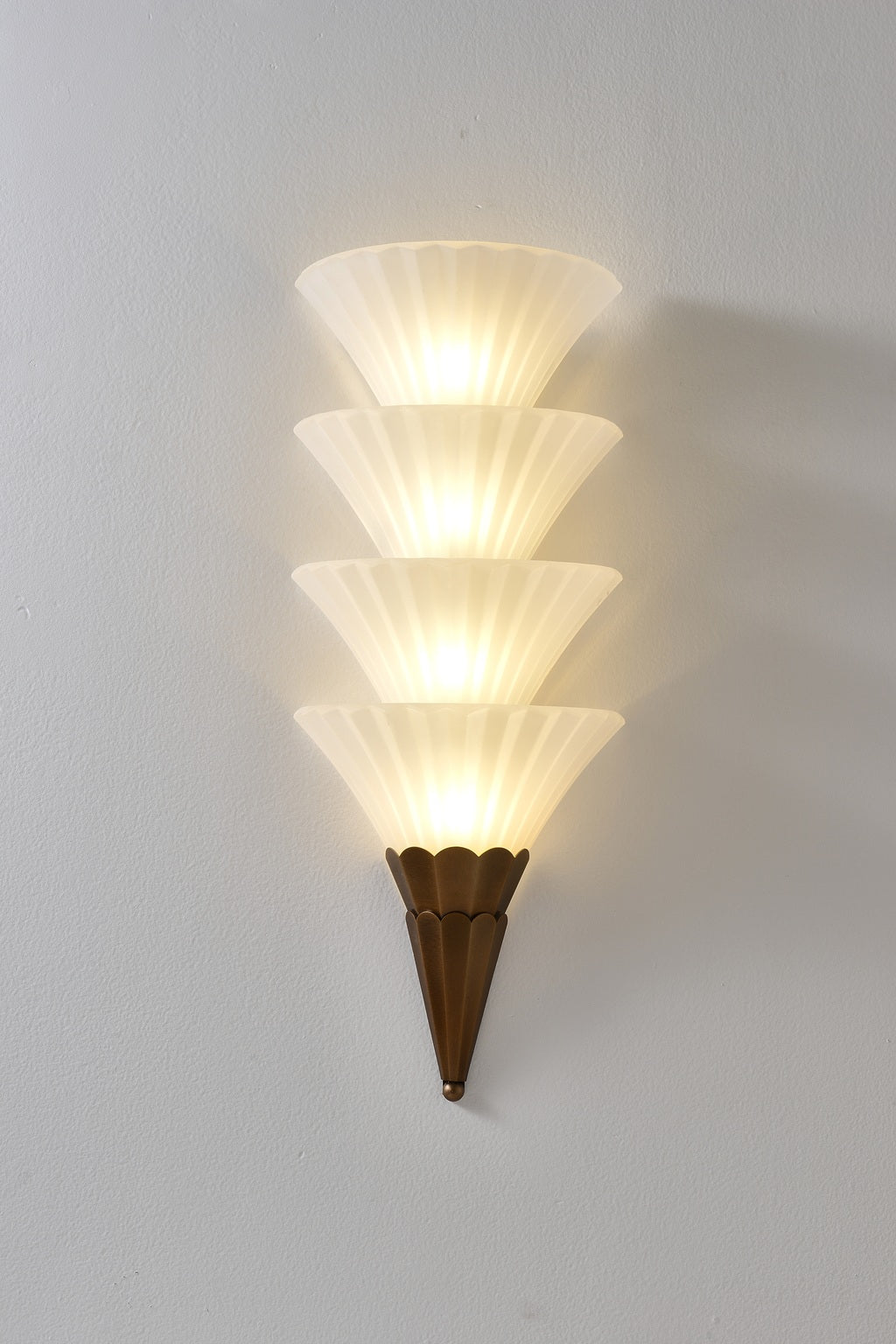 Fanelisse fluted glass wall sconce in Antique Bronze - Four-tier actual front view, warm light