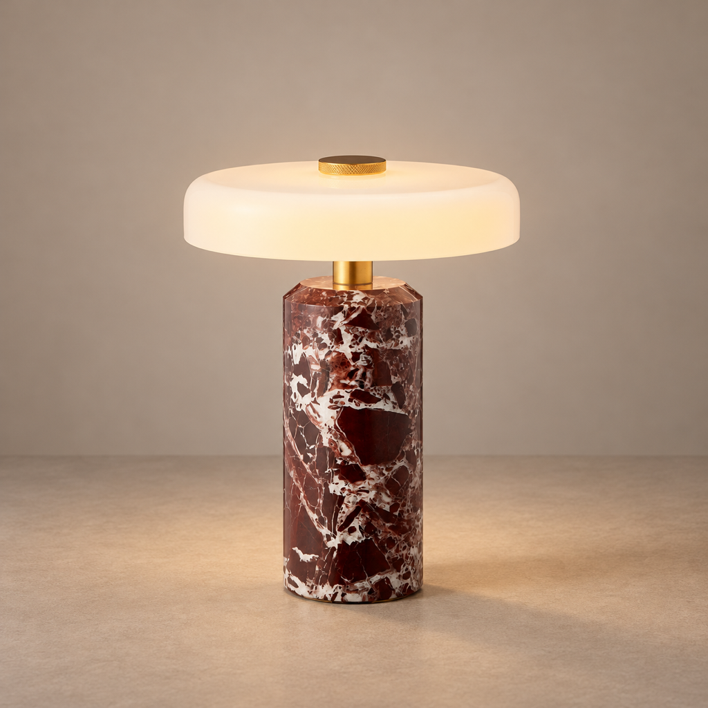 Red marble table lamp with a warm illuminated glass disc shade on a taupe surface