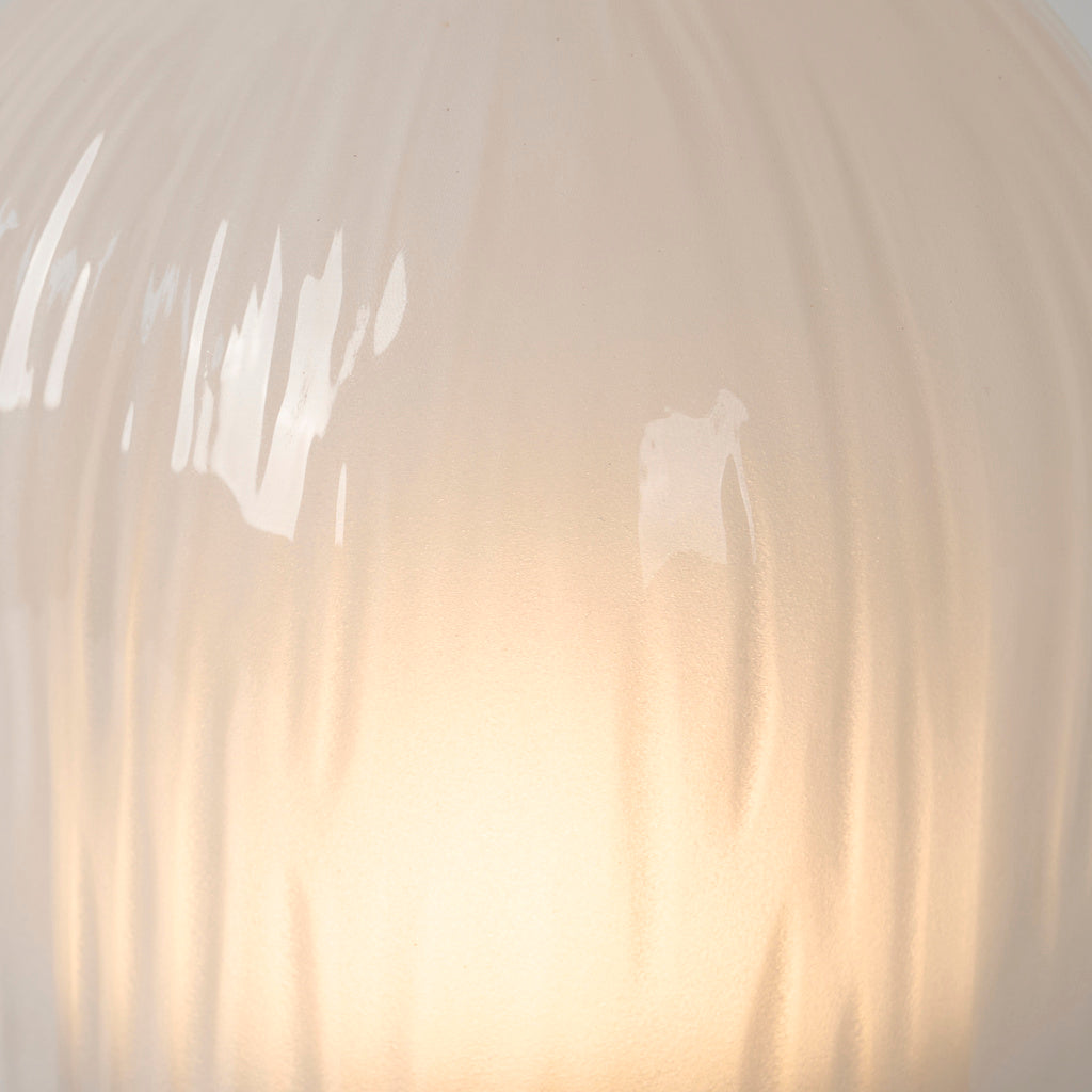 Warm light through the white streaked glass shade of Mernoval table lamp