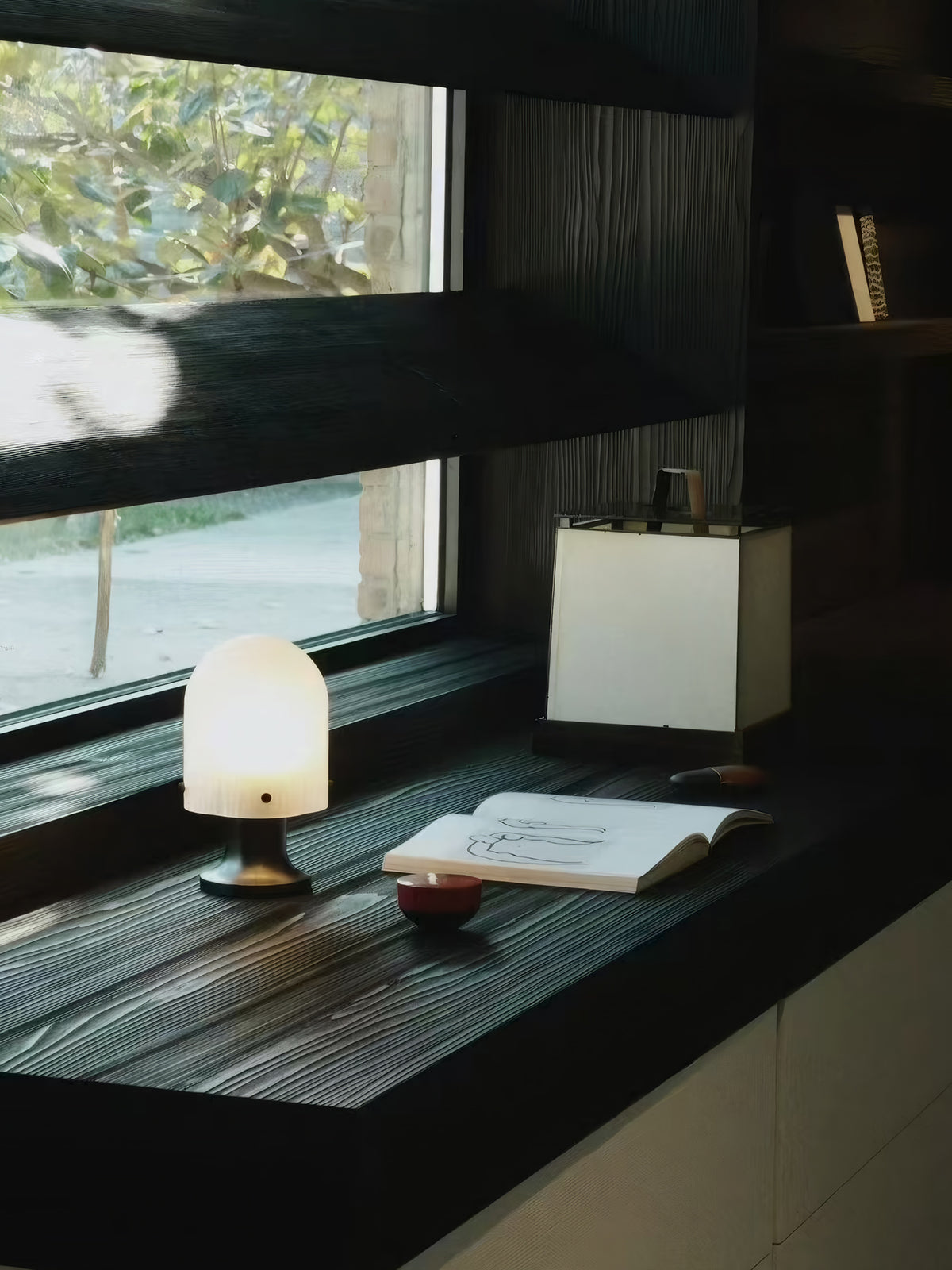 Illuminated Mernoval glass table lamp on an indoor windowsill