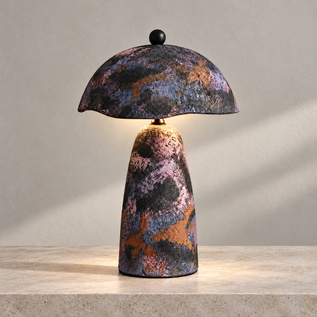 Velmurne hand-painted ceramic table lamp lit on a warm stone surface