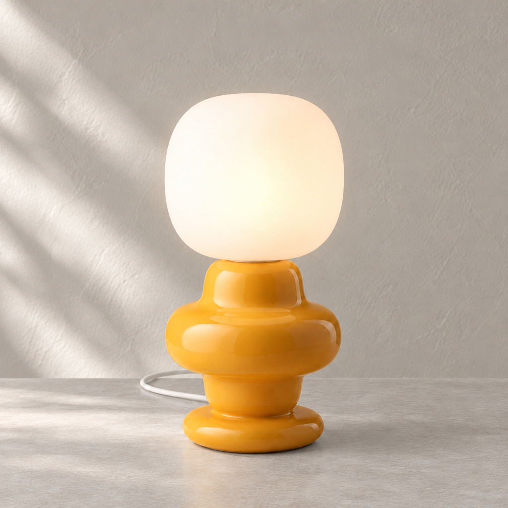 Marunelle yellow ceramic and glass table lamp lit on a warm neutral surface