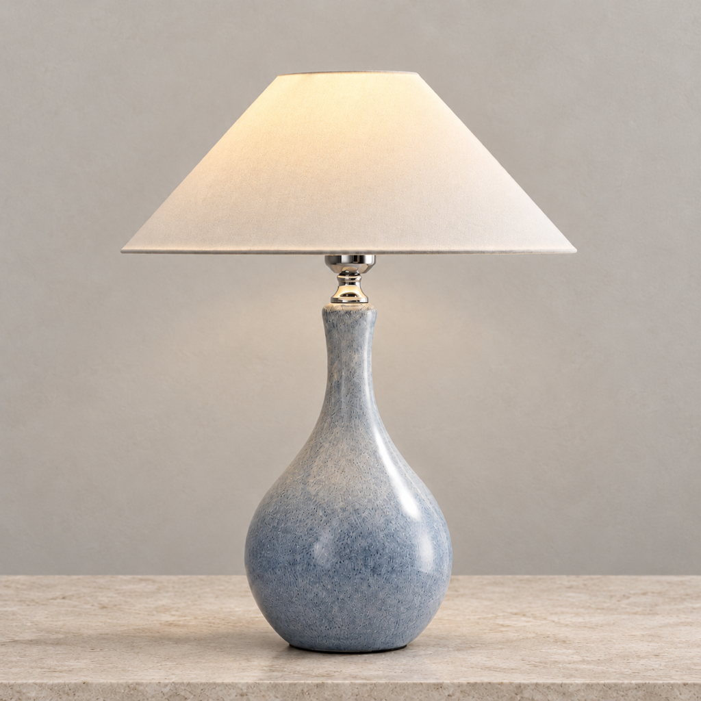 Mist-blue speckled ceramic table lamp with ivory cone fabric shade on a warm beige support