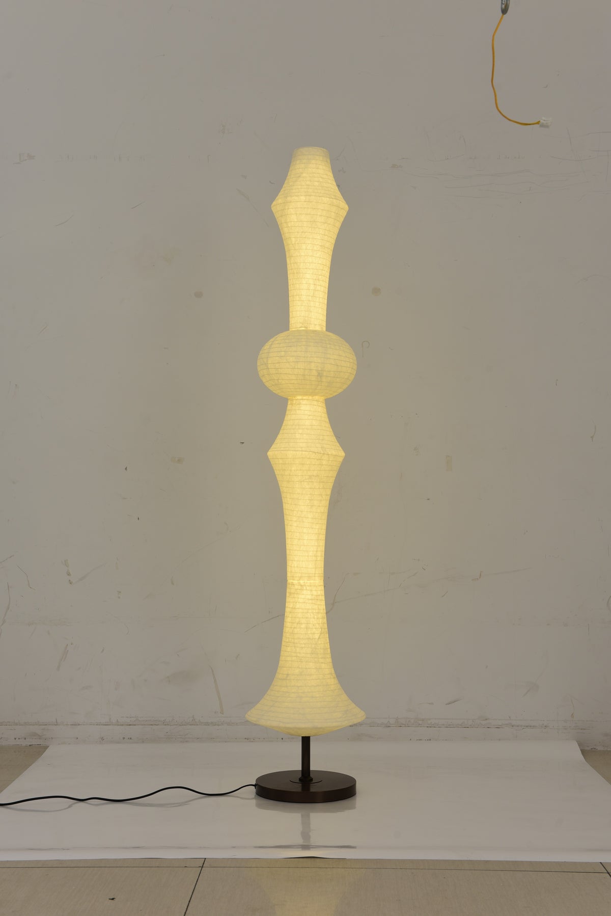 ARDEN LUME Original photograph of the Orlithane silk floor lamp Design A switched on, showing its complete shade, short support and black round base.