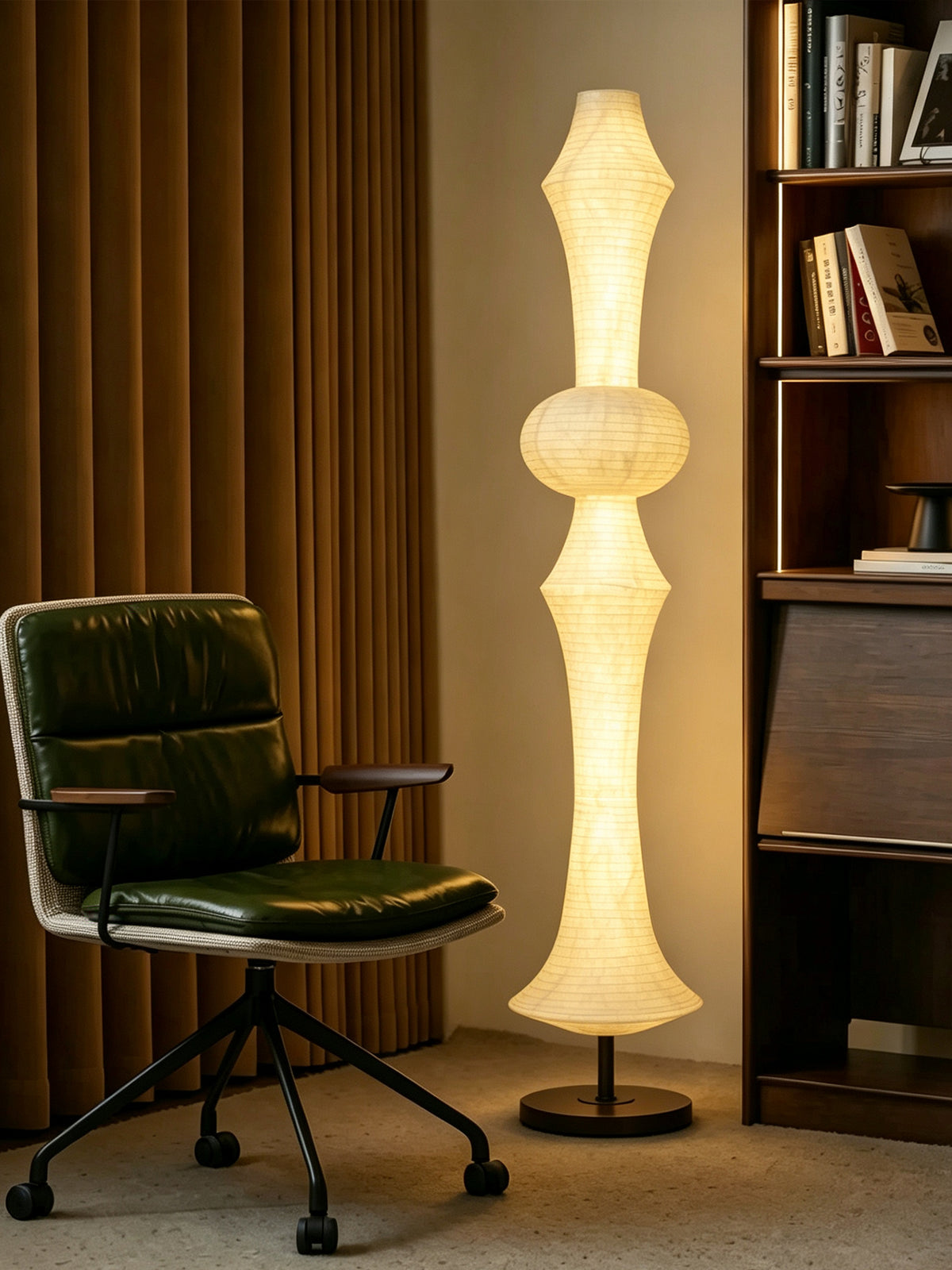 ARDEN LUME Orlithane silk floor lamp Design A switched on beside an olive reading chair and walnut shelves.