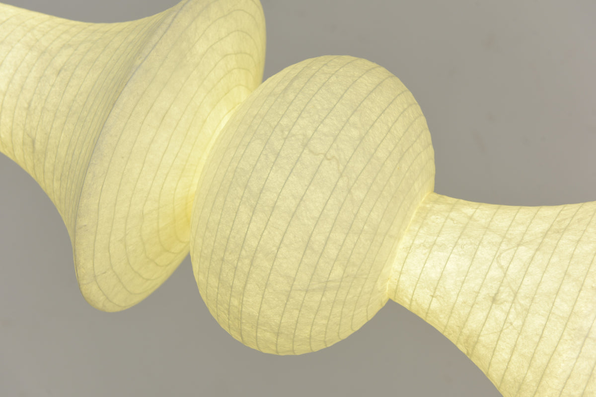 Actual close-up of illuminated Orlithane mulberry silk fabric, the flared shade edge and adjoining globe.