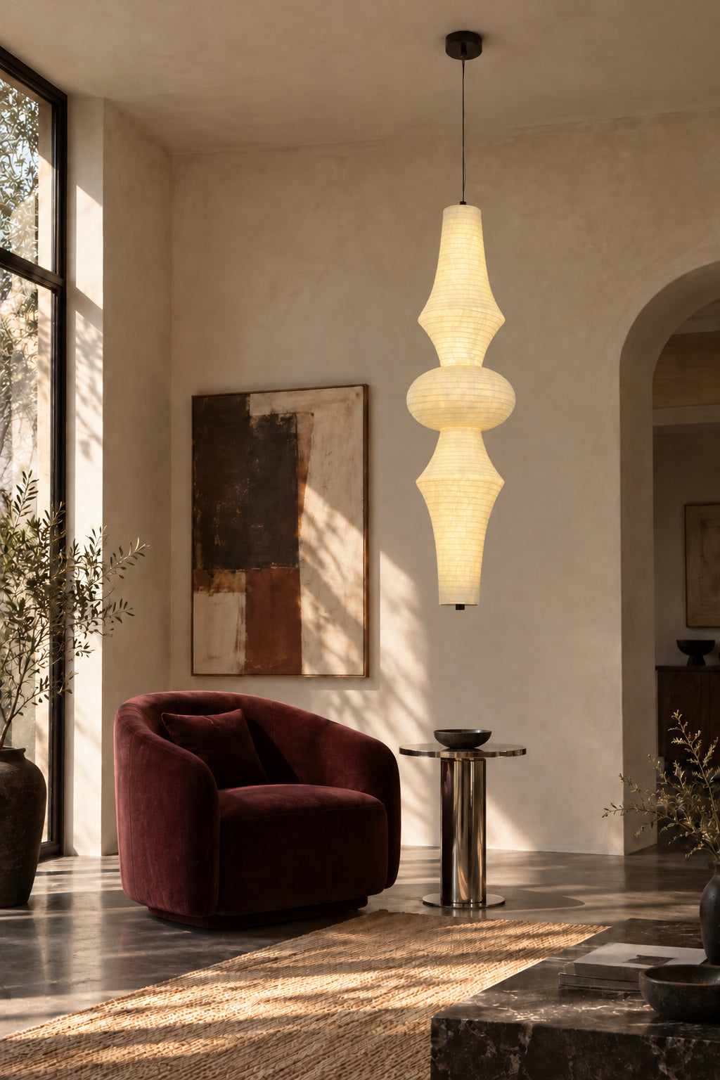 Orlithane mulberry silk pendant design B, lit above a side table beside a red reading chair