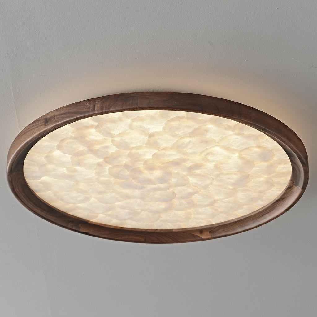 Real photograph of the walnut and shell ceiling light illuminated with warm light