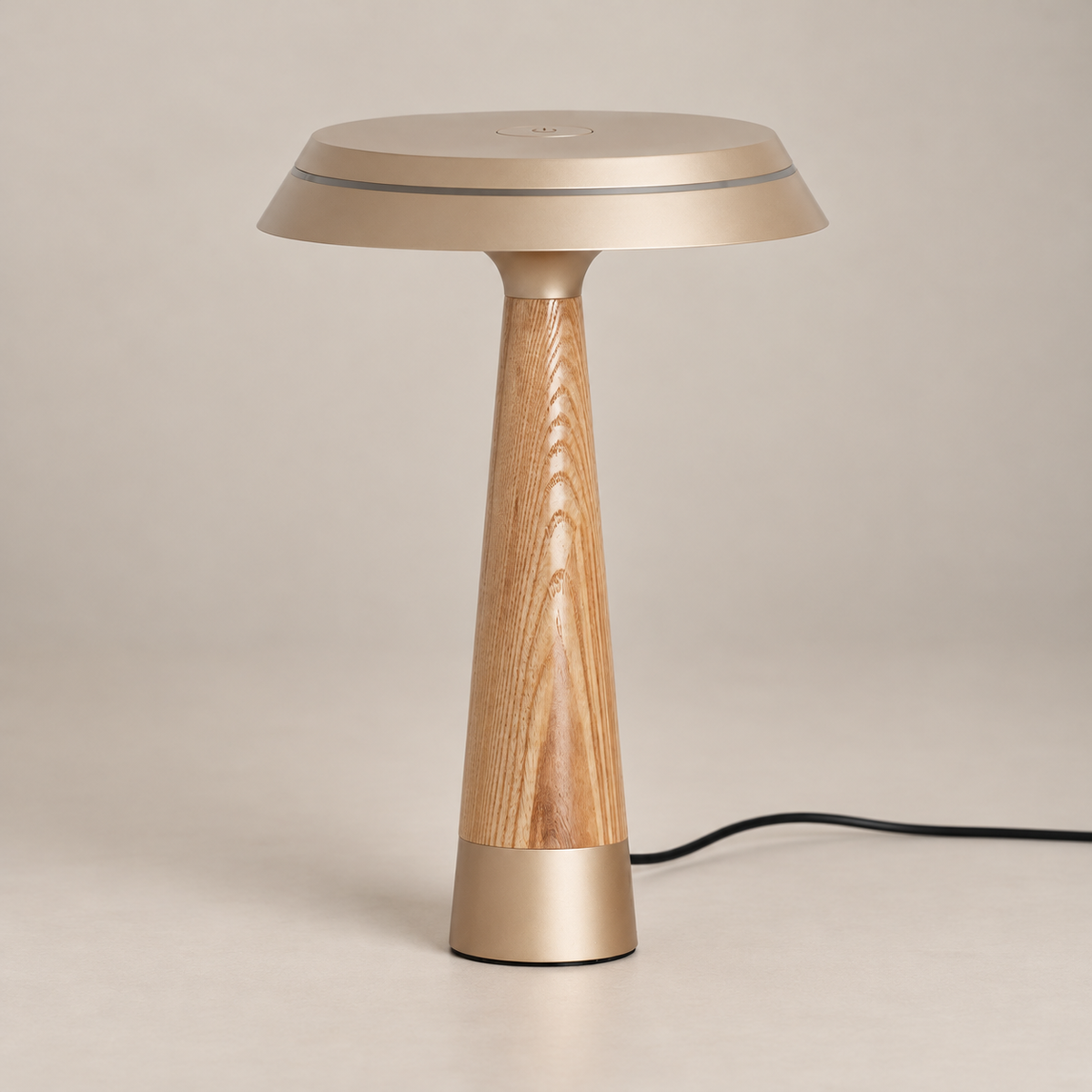 Selvorne Wood Disc Table Lamp. Champagne gold and solid wood table lamp, switched off on a warm neutral background.