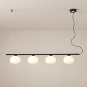 Black four-globe glass linear pendant against a taupe ceiling, turned on