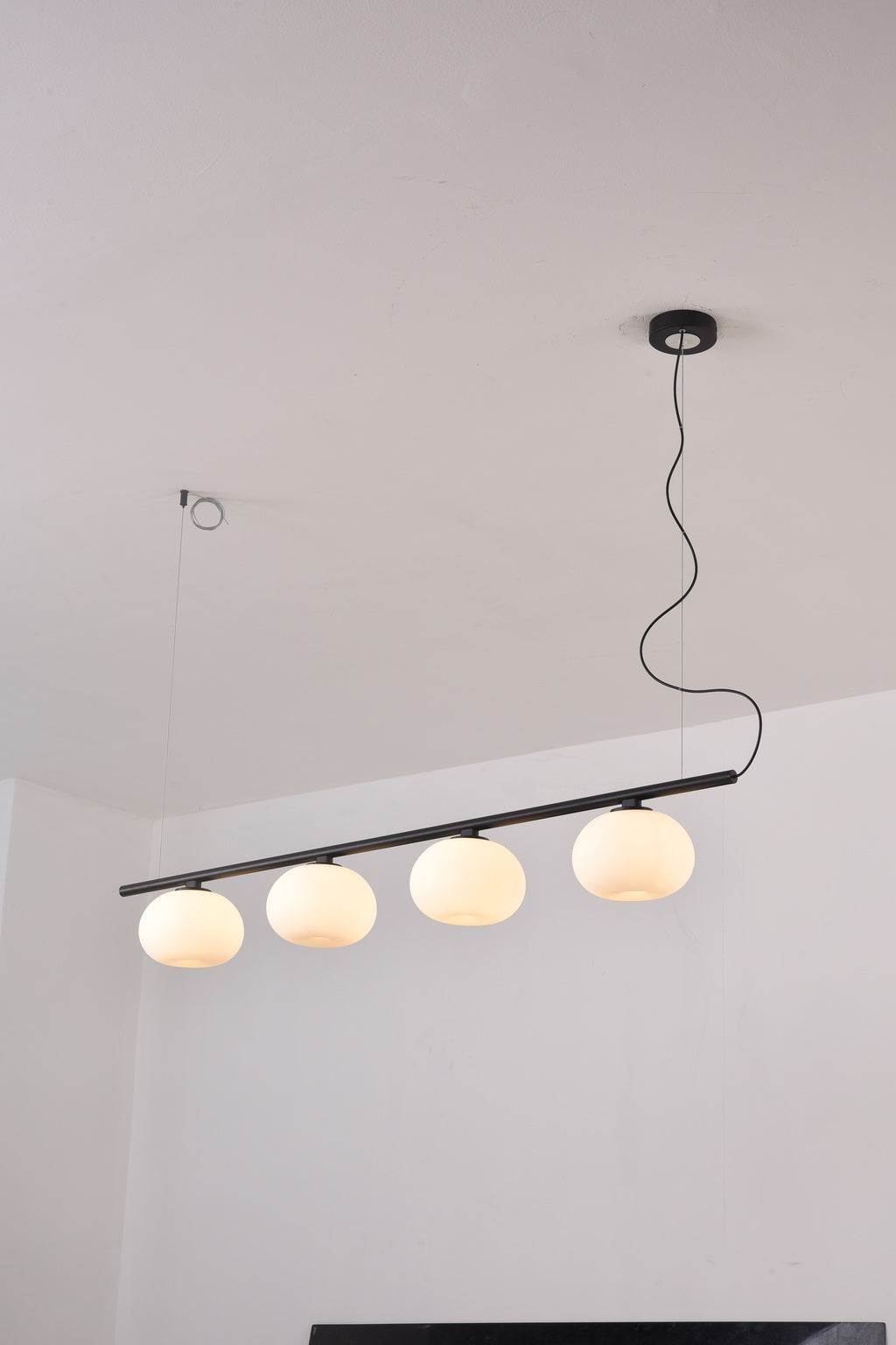 Actual installed Black four-globe glass linear pendant, turned on
