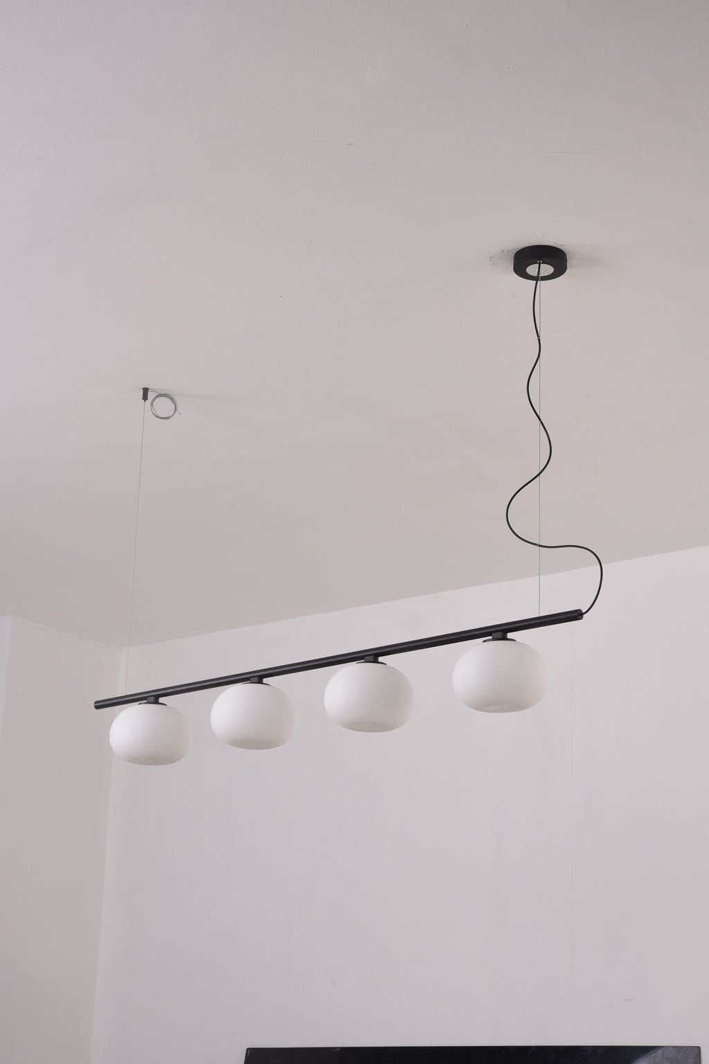Actual installed Black four-globe glass linear pendant, light off
