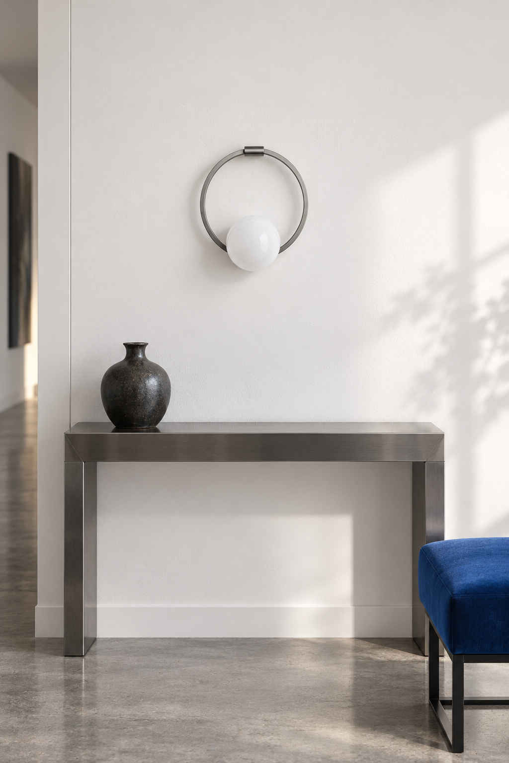 Silver circular ring glass wall sconce above a steel console, light off