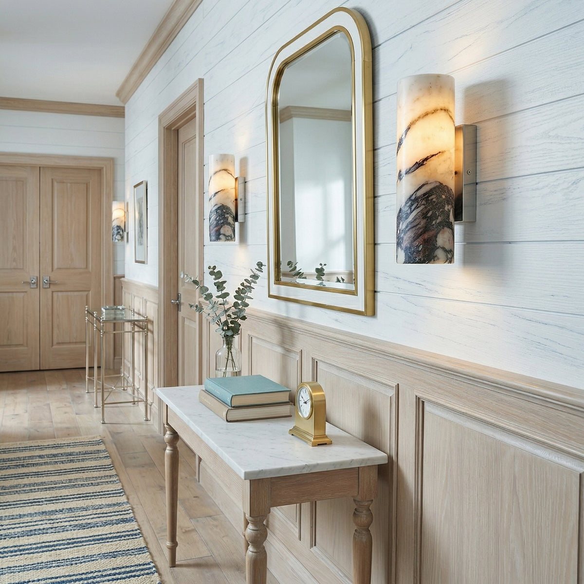 Gold-mounted marble cylinder sconces along an interior wall
