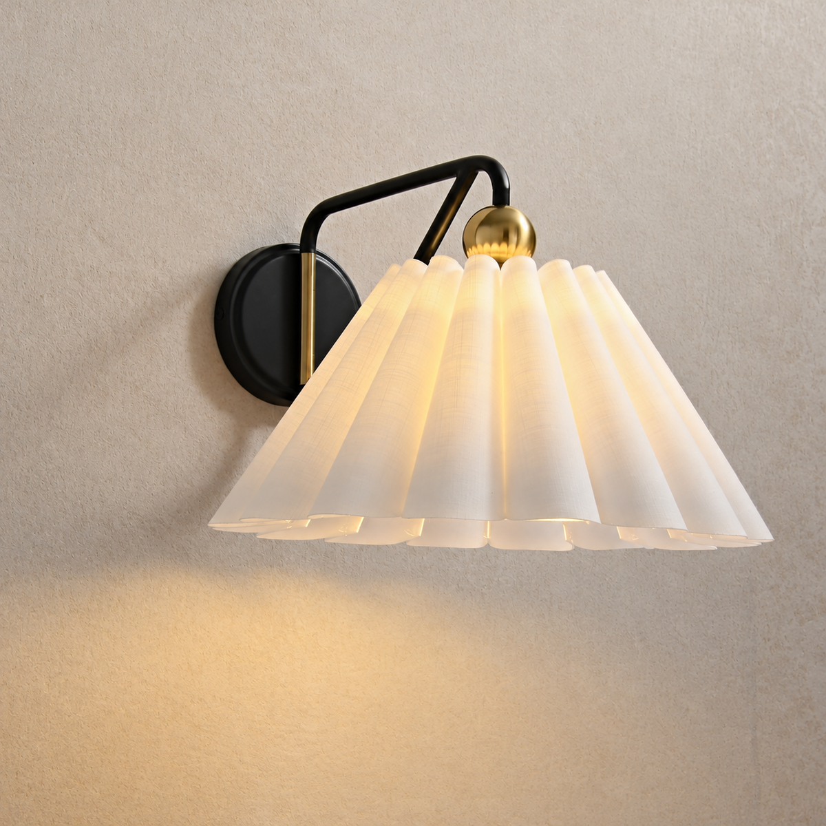 Illuminated white fabric wall sconce casting warm light beneath its pleated shade