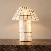 Ivorelle faceted lattice table lamp illuminated on a stone tabletop against a warm neutral wall
