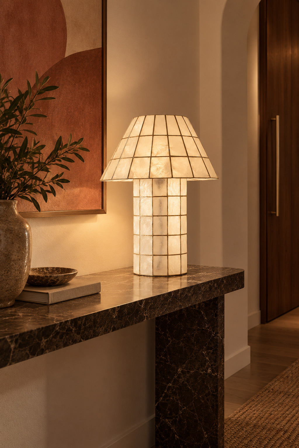 Ivorelle faceted lattice table lamp illuminated on a dark console in a refined entry