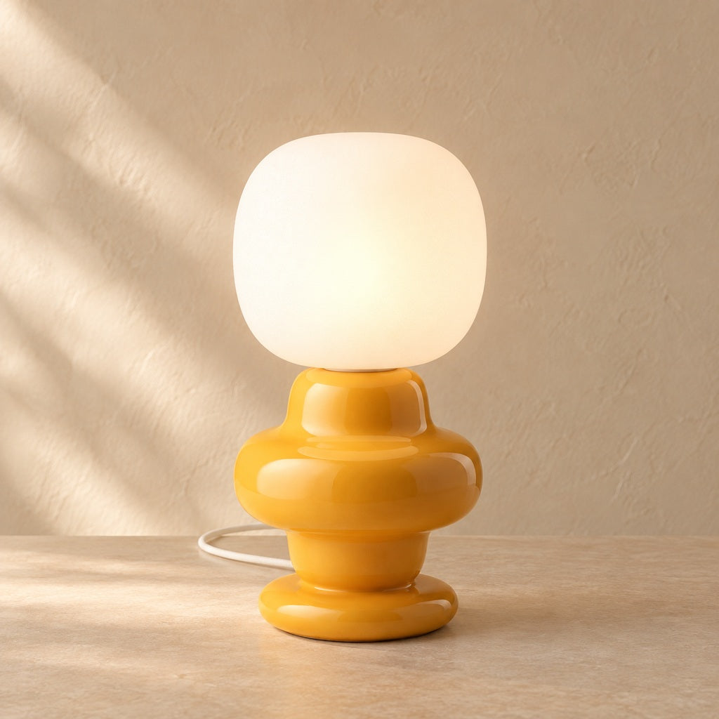 Marunelle yellow ceramic and glass table lamp lit on a warm neutral surface