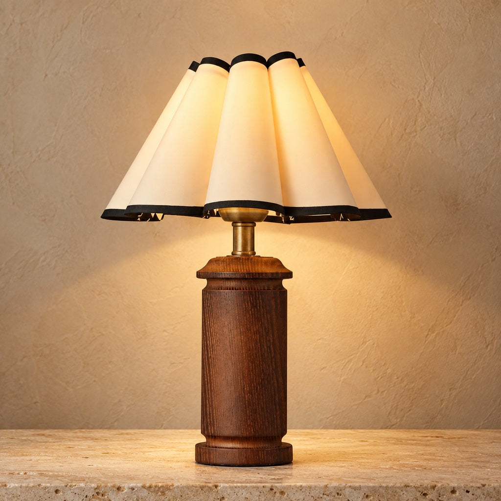 Morivelle pleated shade wood table lamp lit on a warm stone surface