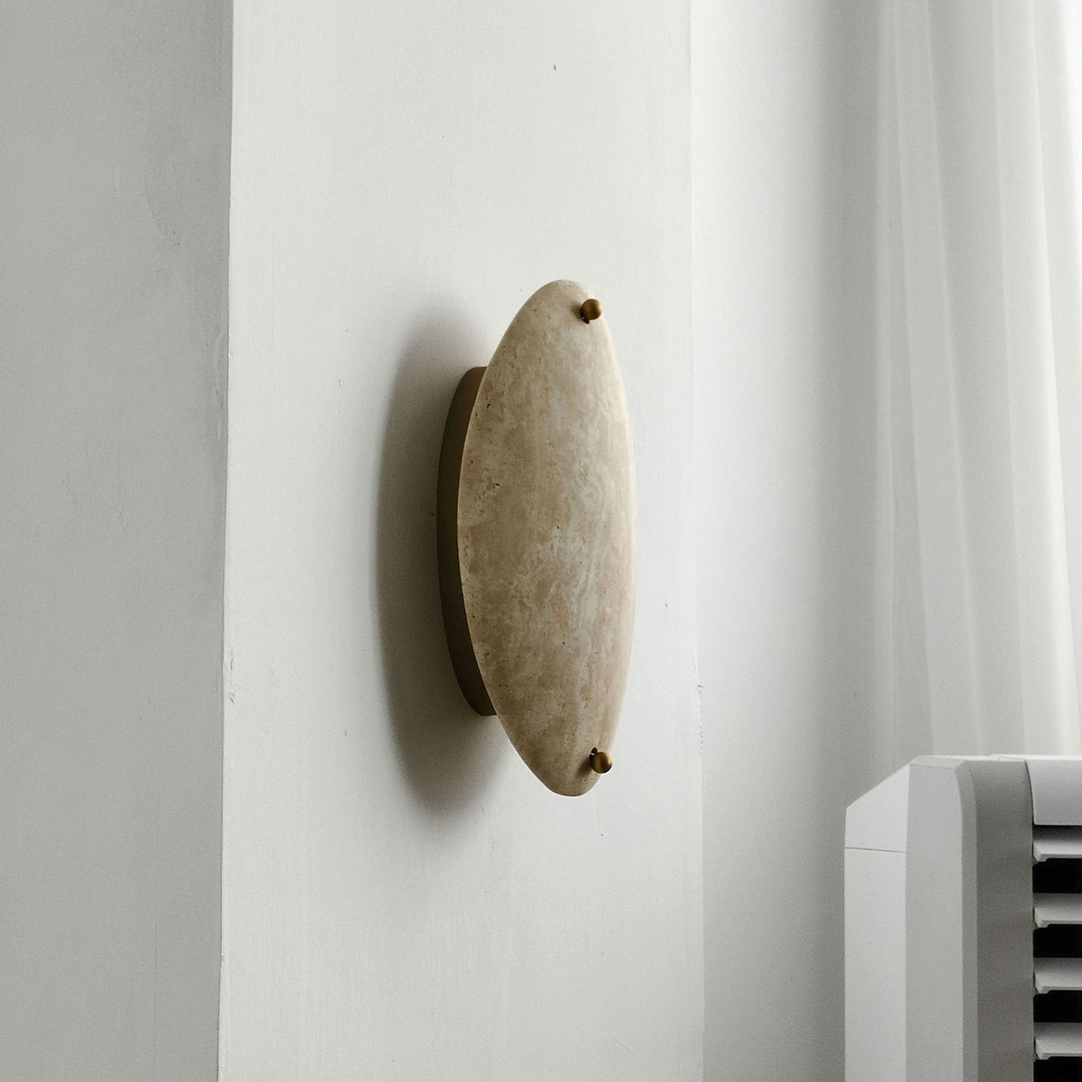 Original real photograph of the unlit beige stone wall sconce, side view.