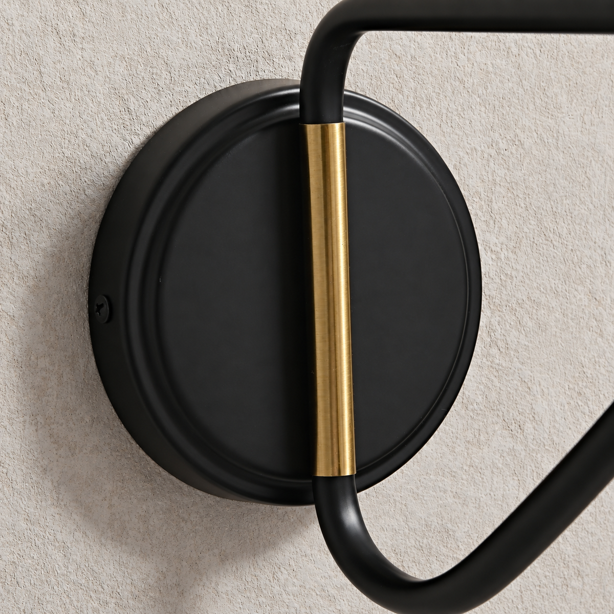 Close-up of the black circular wall mount and brass-tone bracket detail