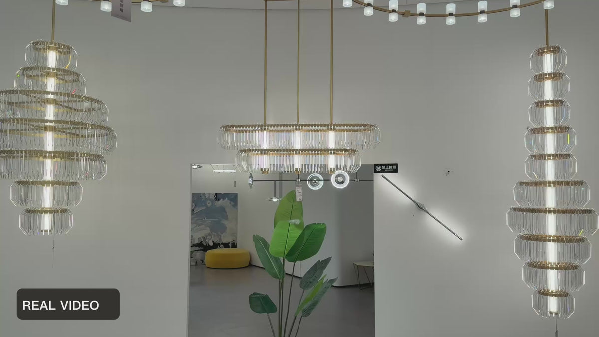 Load video: Arquelle Round Antique Brass Acrylic Tiered Chandelier showroom group real product video — REAL VIDEO · CDE original framing balanced light v1 2026-09-23