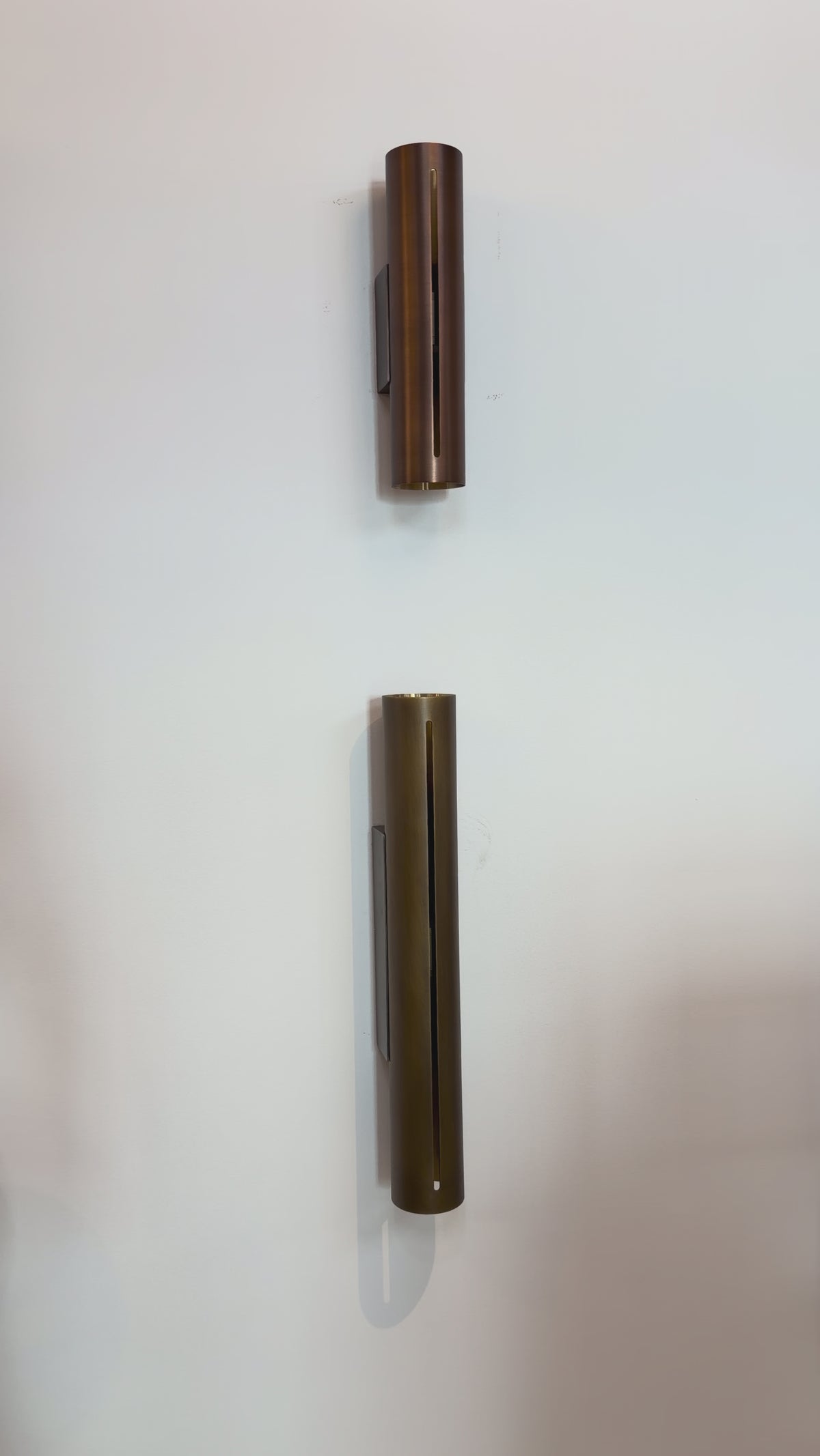 Load video: Minimalist Brass Cylinder Wall Sconce in Antique Brass
