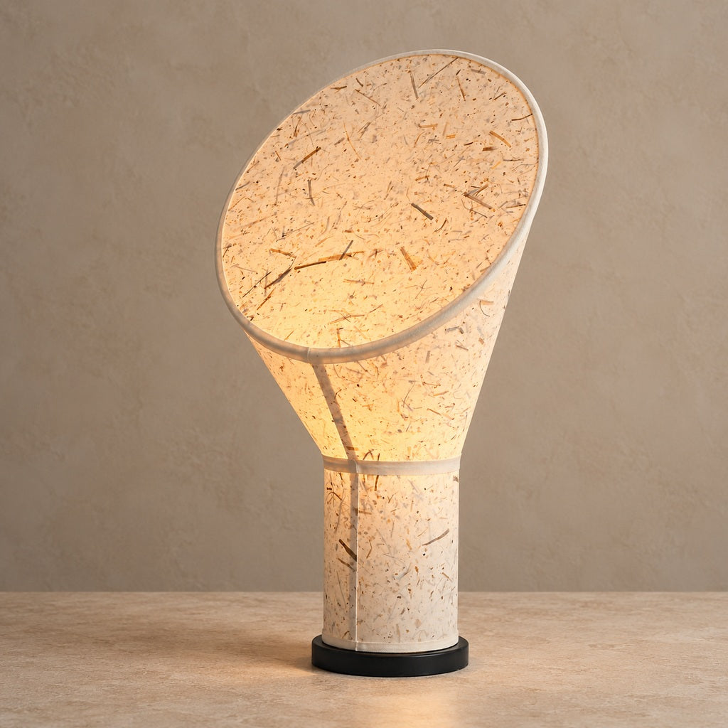 Serevane sculptural fiber paper table lamp lit on a warm stone surface