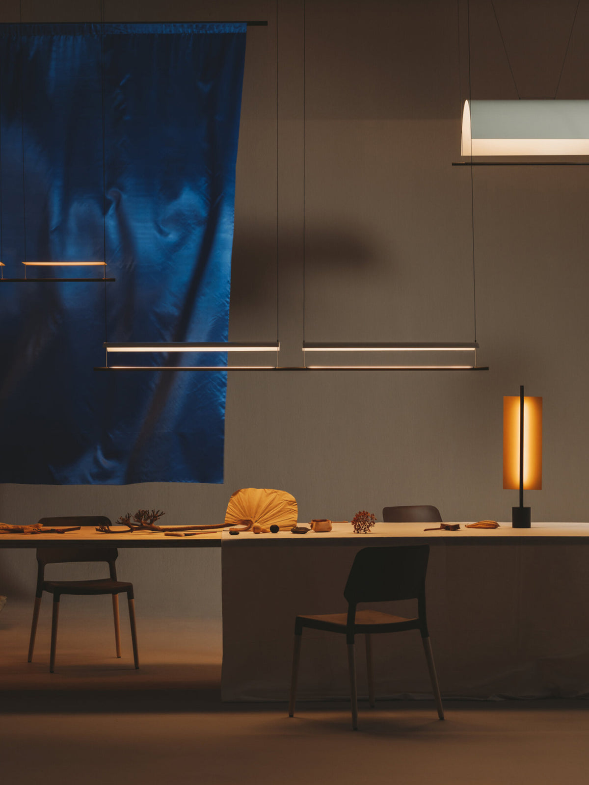 Veilane lighting collection over a long table; fixtures sold separately