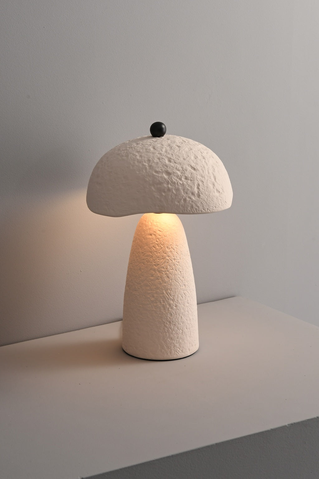Velmurne white ceramic table lamp lit from an angled real-room view