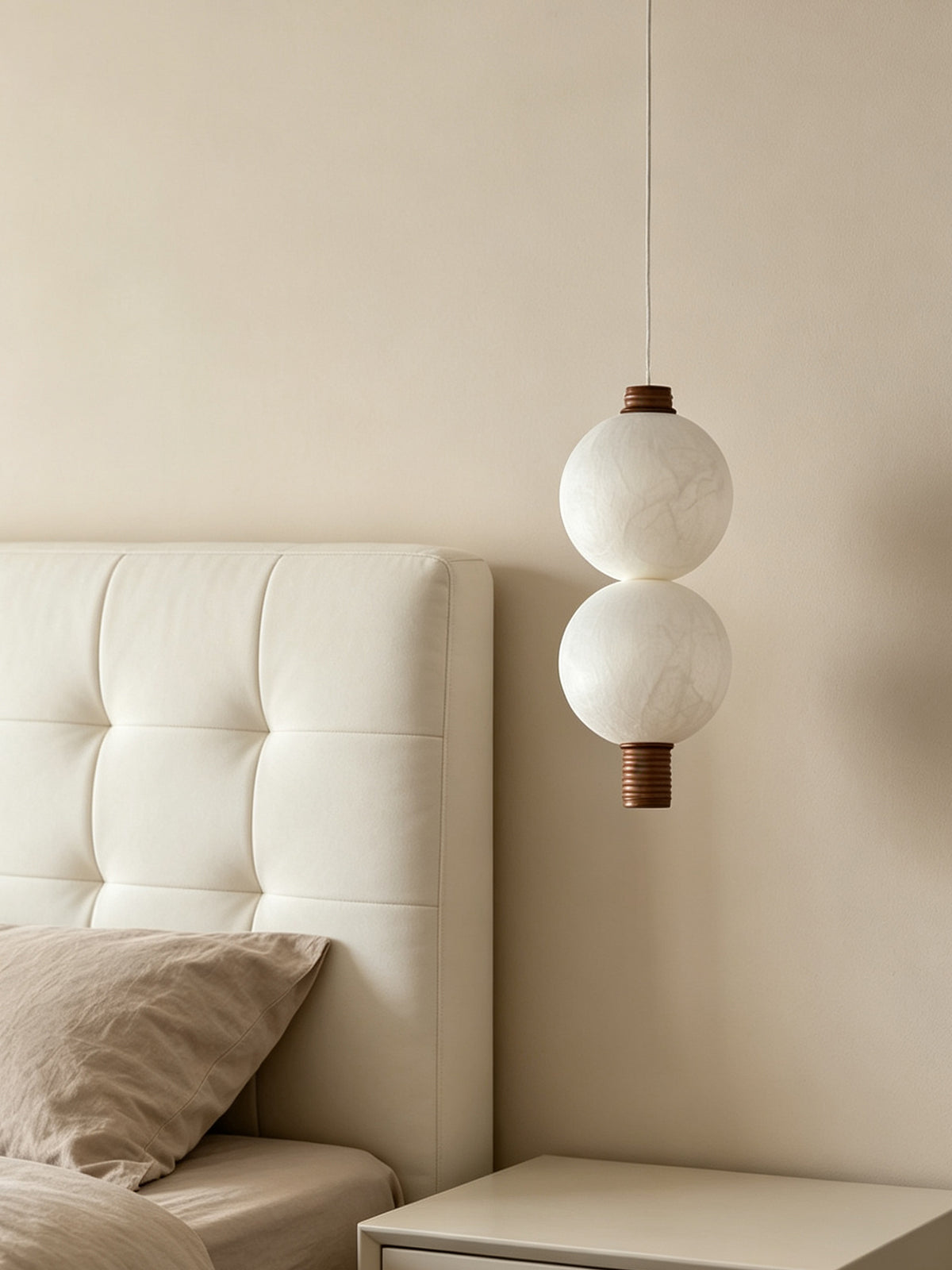 Two-globe natural mulberry silk vertical pendant with dark wood details, unlit beside a bed