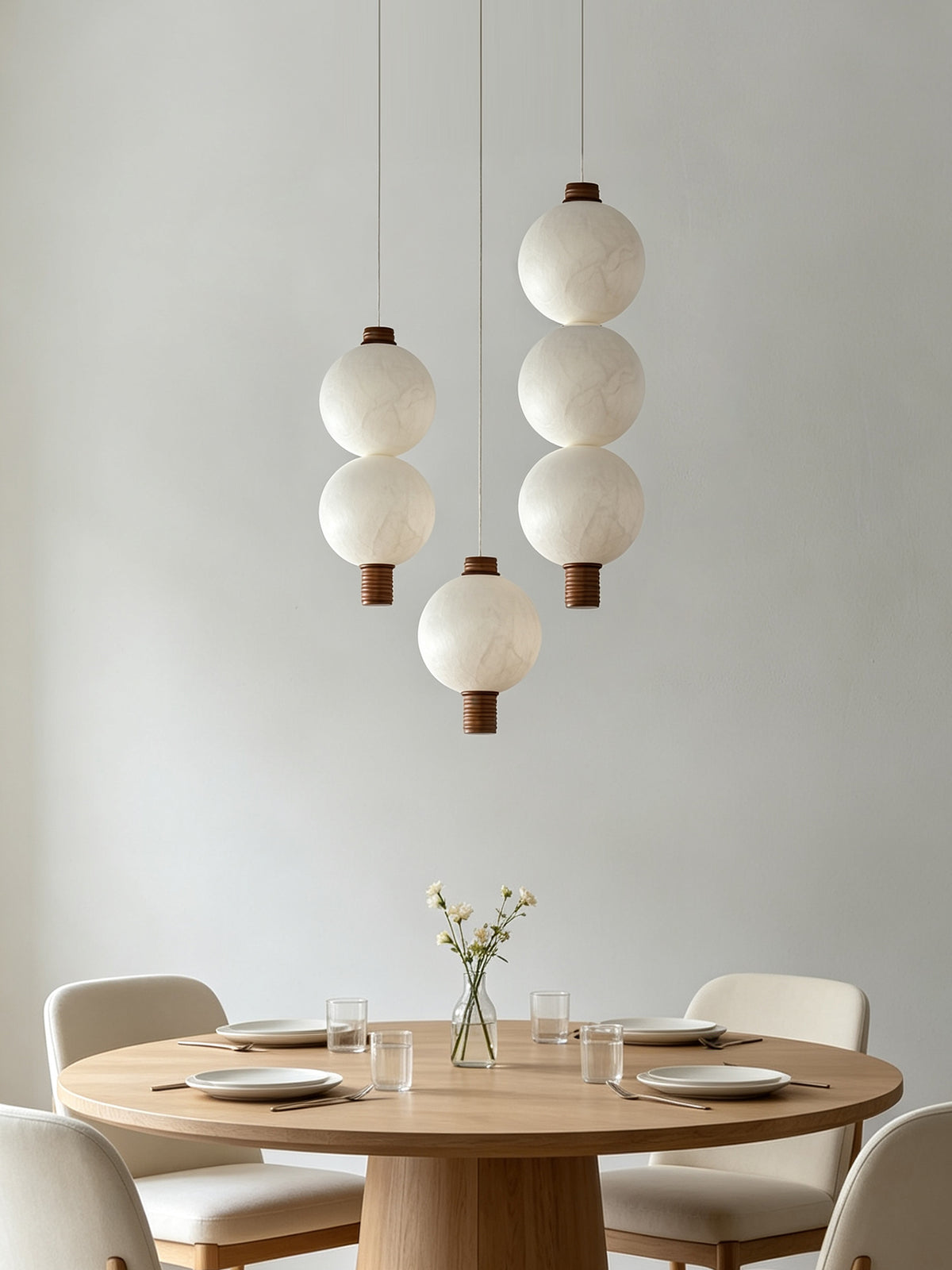 One-, two- and three-globe natural mulberry silk vertical pendants with dark wood details above a dining table; arrangement example
