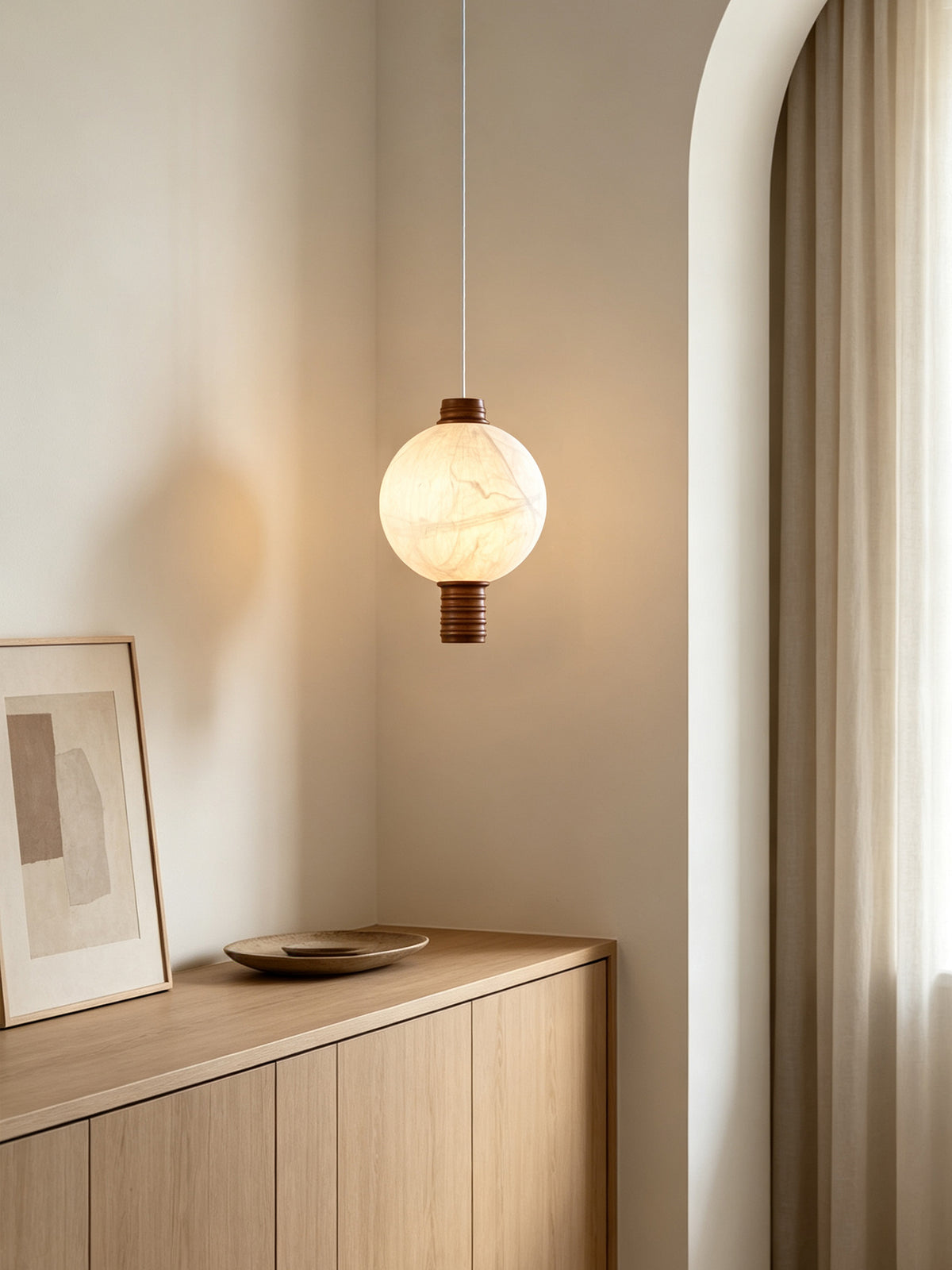 Single-globe natural mulberry silk vertical pendant with dark wood details, lit above an oak sideboard