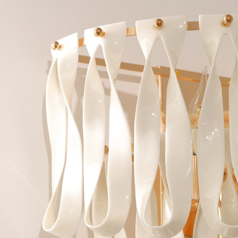 Gold-tone frame and ceramic ribbon attachment detail on the wall sconce