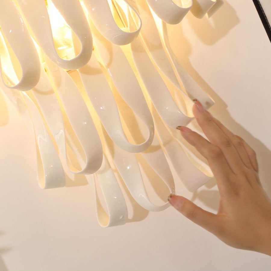 Close view of glossy ivory ceramic ribbon pieces on the wall sconce